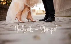 Detailaufnahme von Brautkleid und Anzugschuhen auf Kopfsteinpflaster mit Schriftzug Hochzeits-Stempel